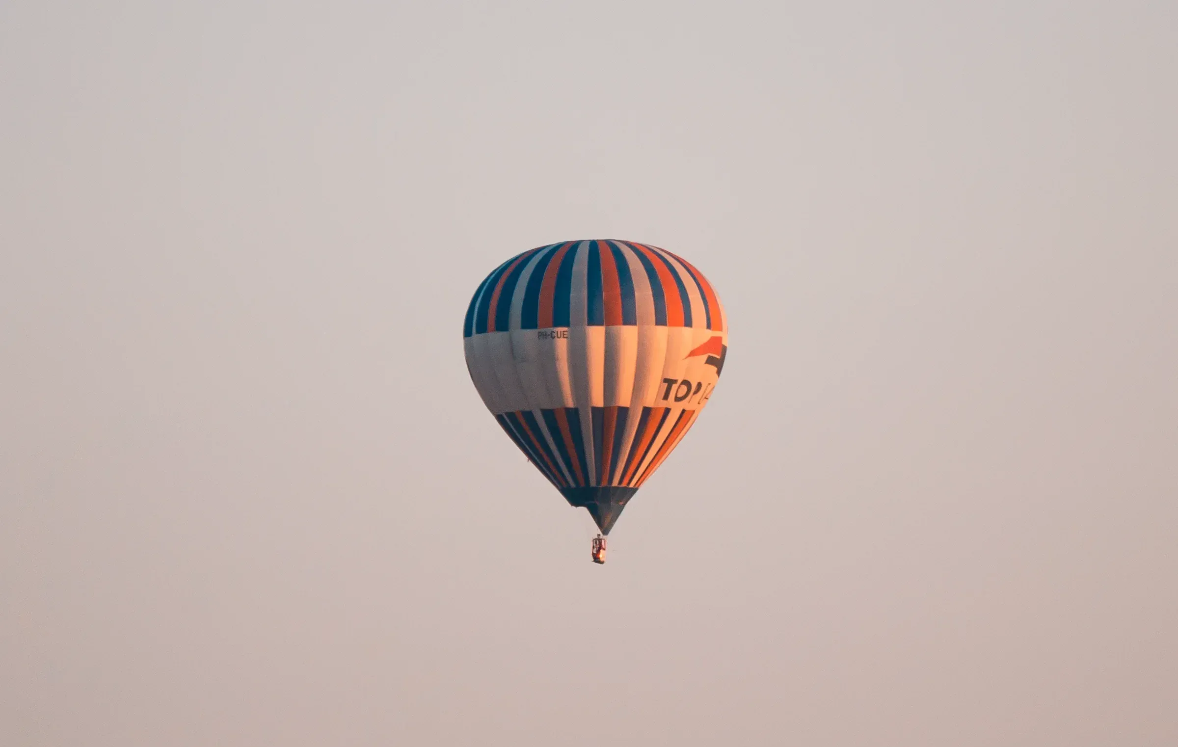 Wide festival scene with balloon and distant crowd, sense of scale against open sky